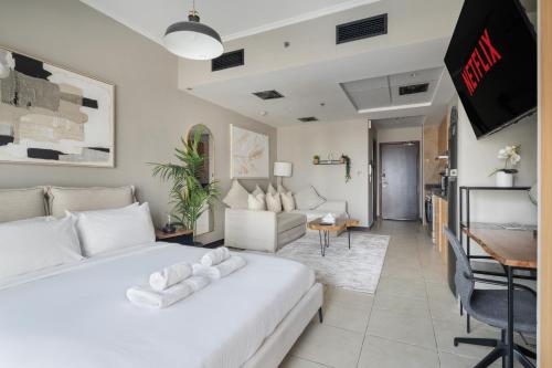 a bedroom with a white bed and a living room at Chic JLT Studio, Lake View, Pool, Metro Access in Dubai