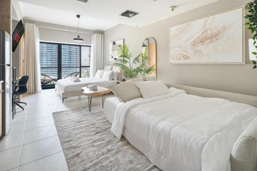 a white bedroom with a large bed and a living room at Chic JLT Studio, Lake View, Pool, Metro Access in Dubai