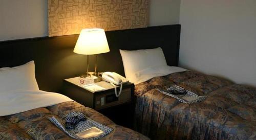 a hotel room with two beds and a telephone at Alpha Hotel Tokushima in Tokushima