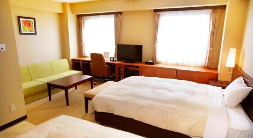 a hotel room with a bed and a desk with a computer at Hotel Naito Kofu Showa in Kofu
