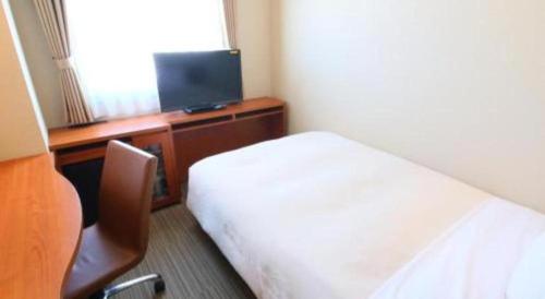 a bedroom with a bed and a desk with a television at Hotel Naito Kofu Showa in Kofu