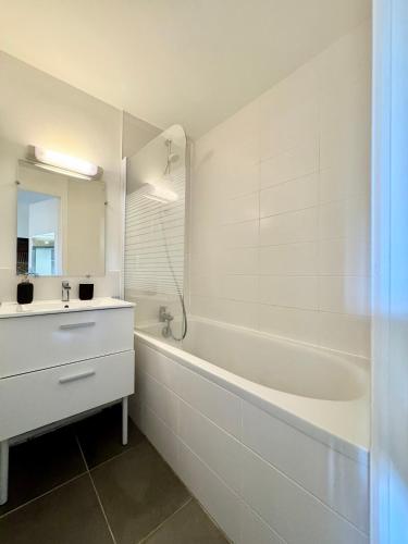 a white bathroom with a sink and a tub and a mirror at Le Saint Georges avec terrasse, Hyper centre ville in Rennes