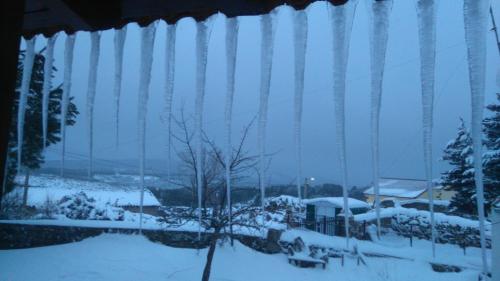 a view through a window of a snow covered yard at Hotel Rural La Dehesilla in Barajas de Gredos