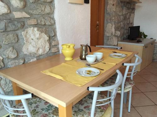 Una mesa de madera con sillas y un jarrón amarillo encima. en Casa Margherita, en Brenzone sul Garda