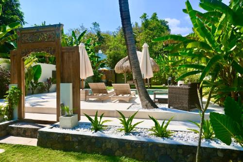 een patio met stoelen en parasols in een tuin bij Villa Benih Cinta in Lovina