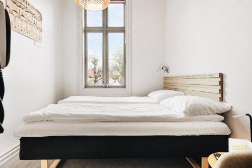 a bed in a white room with a window at Klosterhagen Hotel in Bergen