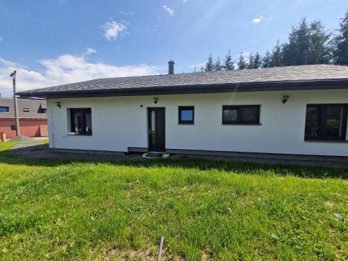 a white house with a grass yard at Chalupa Jasanka in Červená Voda