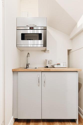 a kitchen with white cabinets and a microwave at Klosterhagen Hotel in Bergen