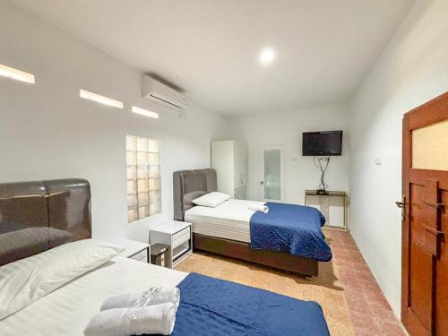 a bedroom with two beds and a flat screen tv at Tini's Guest House Malang Mitra RedDoorz in Betek