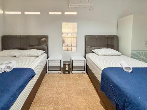 a room with two beds with blue and white sheets at Tini's Guest House Malang Mitra RedDoorz in Betek