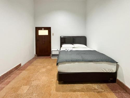 a bedroom with a bed in a room with a door at Tini's Guest House Malang Mitra RedDoorz in Betek