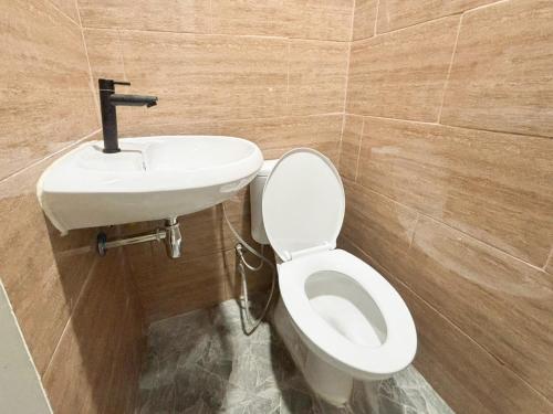 a bathroom with a toilet and a sink at Tini's Guest House Malang Mitra RedDoorz in Betek
