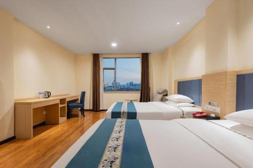 a hotel room with two beds and a desk at JTOUR Inn Xiantao Shopping Mall Pedestrian Street in Xiantao