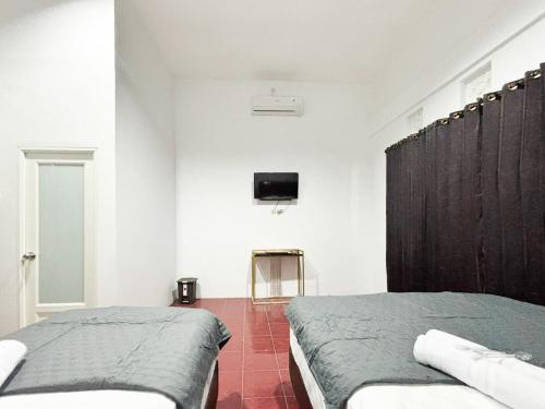 a bedroom with two beds and a tv on the wall at Tini's Guest House Malang Mitra RedDoorz in Betek