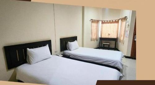 two beds in a hotel room with white sheets at Mark Four Place Hotel in Phrae