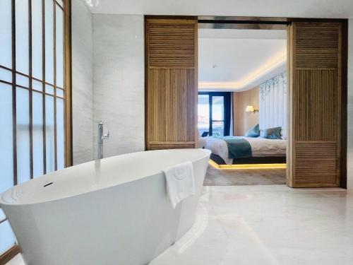 a bathroom with a tub and a bedroom with a bed at Kunming Dianchi Garden Hotel & Spa in Kunming