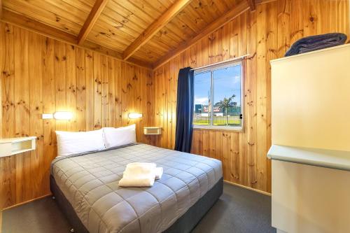 a bedroom with a bed in a wooden room at Pacific Gardens Village in Heatherbrae