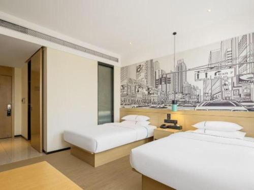 two beds in a hotel room with a drawing on the wall at City Comfort Inn Ji'an South Administrative Center in Ji'an