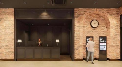 a man standing in a lobby with a clock on the wall at HOTEL D EDITION in Daejeon