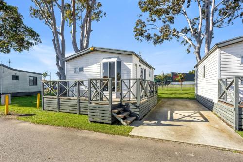 a tiny house with a porch next to two buildings at Heatherbrae Holiday Village in Heatherbrae
