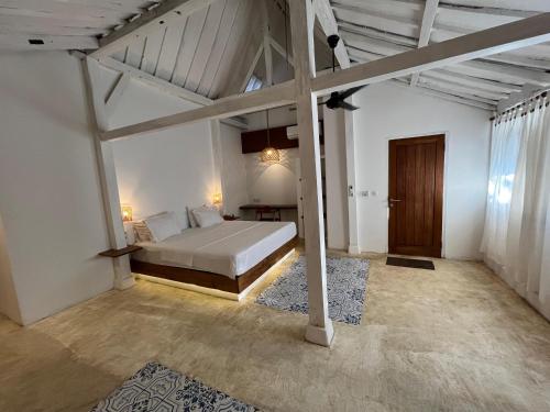 a bedroom with a bed in a white room at Omah Gili Hotel in Gili Air
