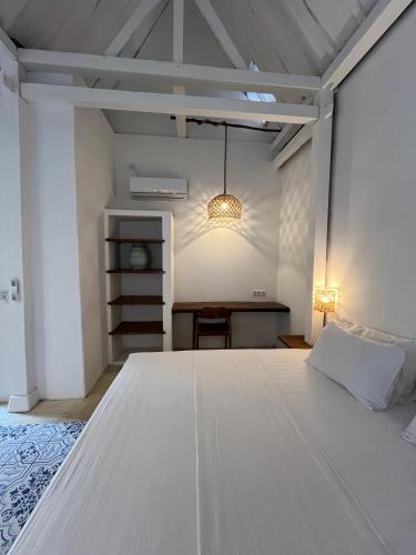 a large white bed in a room with a table at Omah Gili Hotel in Gili Air
