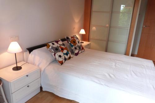 a small bedroom with a white bed and a lamp at Apartamentos Noluna in Segovia