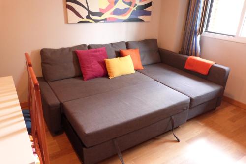 a couch with colorful pillows on it in a living room at Apartamentos Noluna in Segovia