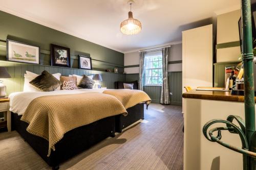 a bedroom with a large bed with green walls at The Windmill On The Common in London