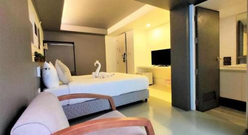 a bedroom with a large white bed and a television at Silom Studios in Bangkok