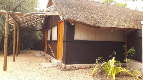 a small black building with a thatched roof at Off Beat Safaris Bush Lodge in Hoedspruit