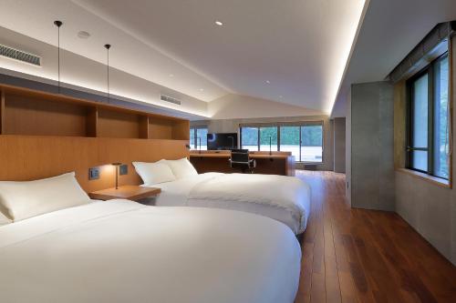 a hotel room with two beds and a desk at Shin Toji Hotel Lulud in Nakanojo