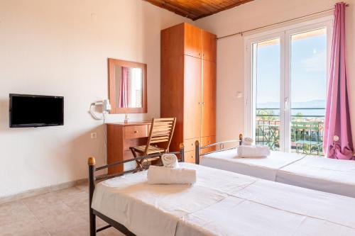 Un dormitorio con dos camas y una gran ventana. en Gavriil Apartments, en Corfu