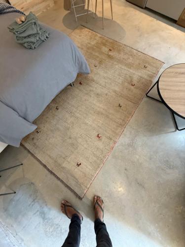 a person with their feet on a rug next to a bed at Studio du Cherche Midi in Jarnac