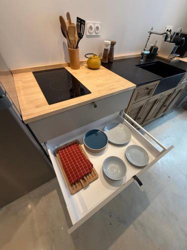 a kitchen with a counter with dishes on a shelf at Studio du Cherche Midi in Jarnac