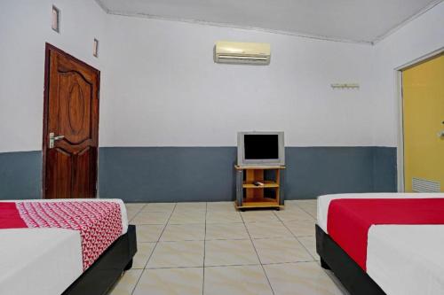 a room with two beds and a tv on a table at OYO 90405 Penginapan Sasti Kuningan in Kuningan