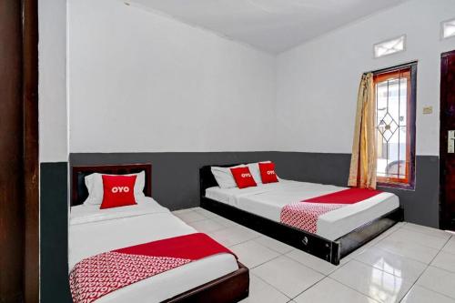 two beds in a room with red and white pillows at OYO 90405 Penginapan Sasti Kuningan in Kuningan