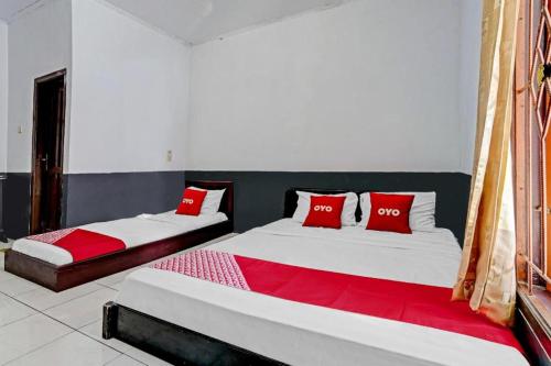 two beds in a room with red and white pillows at OYO 90405 Penginapan Sasti Kuningan in Kuningan