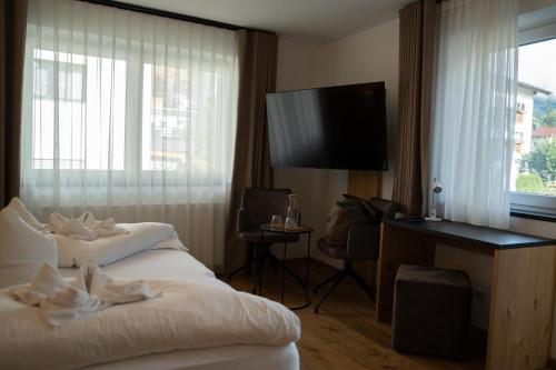 a hotel room with a bed and a flat screen tv at Alpenhotel Regina in Nauders