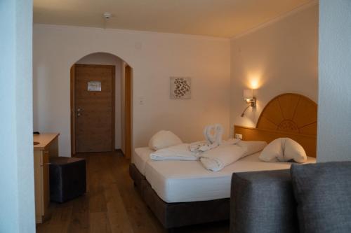a hotel room with a bed with white pillows at Alpenhotel Regina in Nauders