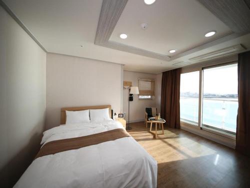 a bedroom with a large bed and a large window at Hotel Aroha Jeju in Seogwipo