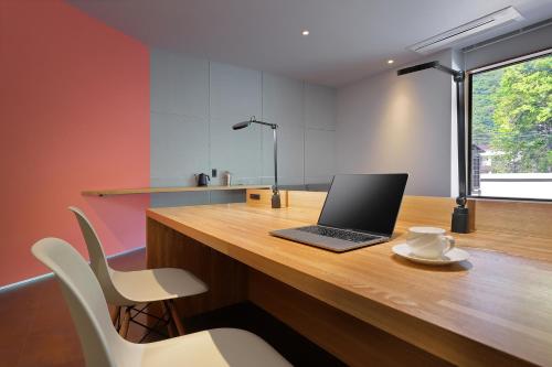 a laptop computer sitting on a wooden desk with chairs at Shin Toji Hotel Lulud in Nakanojo