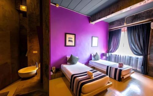 a purple room with two beds and a bath tub at The B Ranong Trend Hotel in Ranong