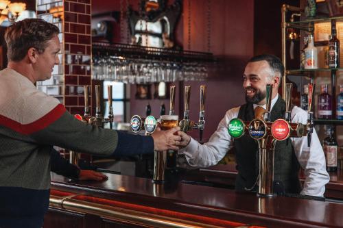 a bartender handing a man a drink at a bar at Hotel Indigo London Clerkenwell by IHG in London