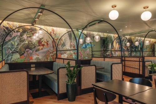 a restaurant with tables and chairs and a mural at Hotel Indigo London Clerkenwell by IHG in London