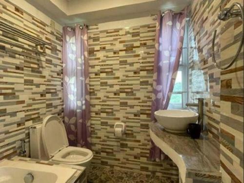 a bathroom with a toilet and a sink and a window at Pilot Hotel in Alaminos