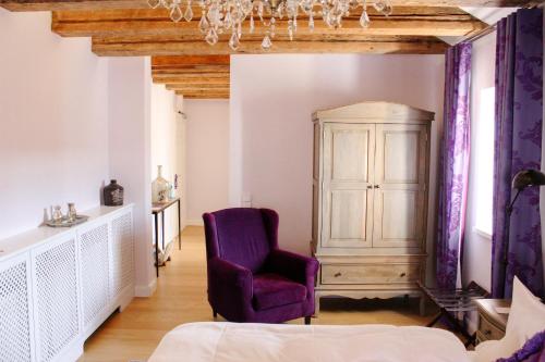 a bedroom with a purple chair and a cabinet at Gästehaus im Weingut am Nil in Kallstadt