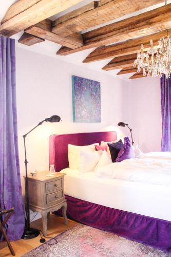 a bedroom with a white bed with purple curtains at Gästehaus im Weingut am Nil in Kallstadt