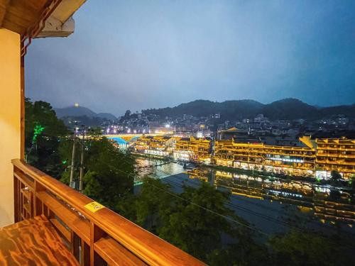 a view from a balcony of a city at night at Ronghe River View Homestay in Fenghuang