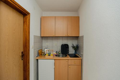 a small kitchen with wooden cabinets and a sink at Villa Green Mak in Neum